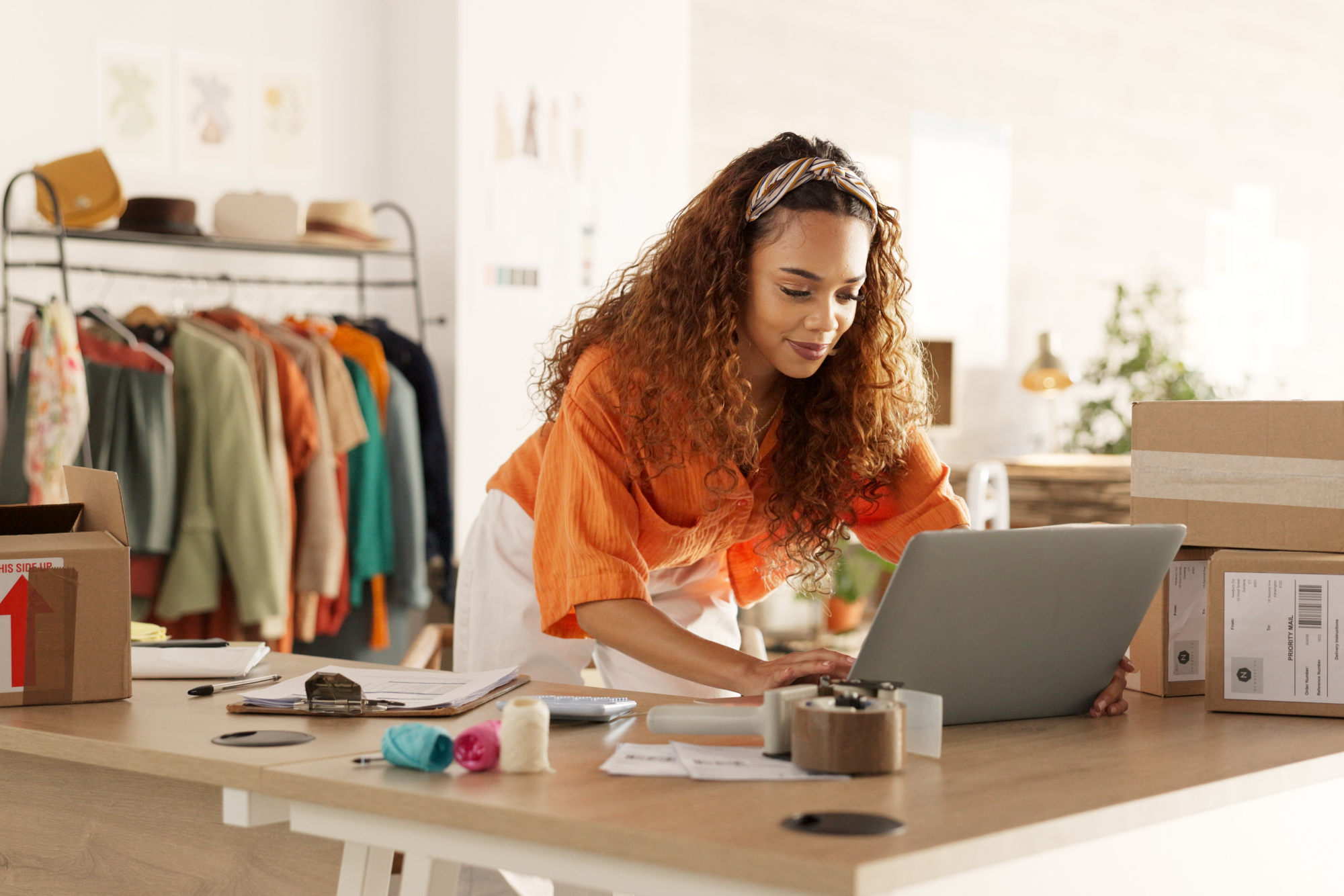 A retail store owner updates her online marketing presence via her laptop