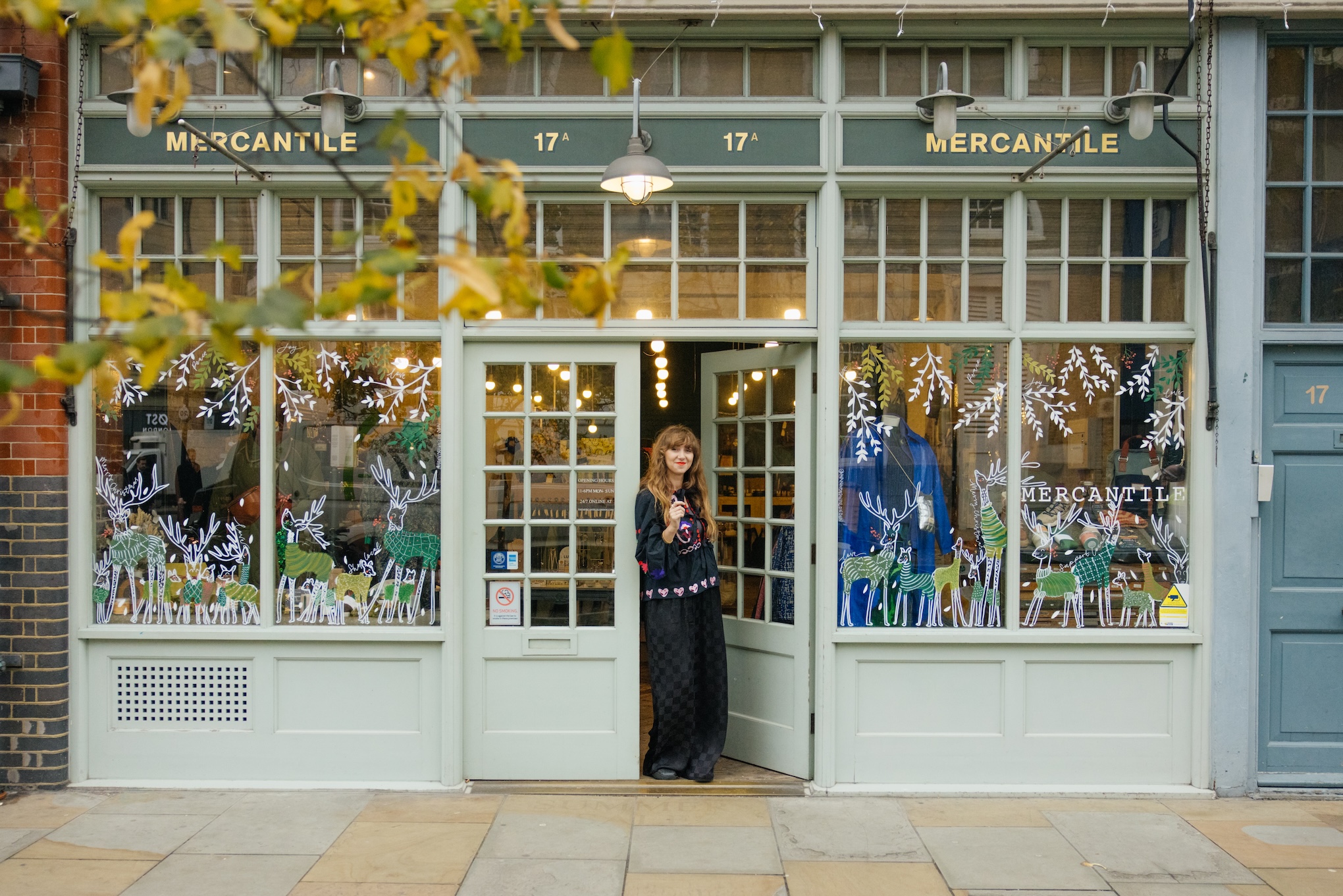 a shopkeeper stands in the doorway of her store