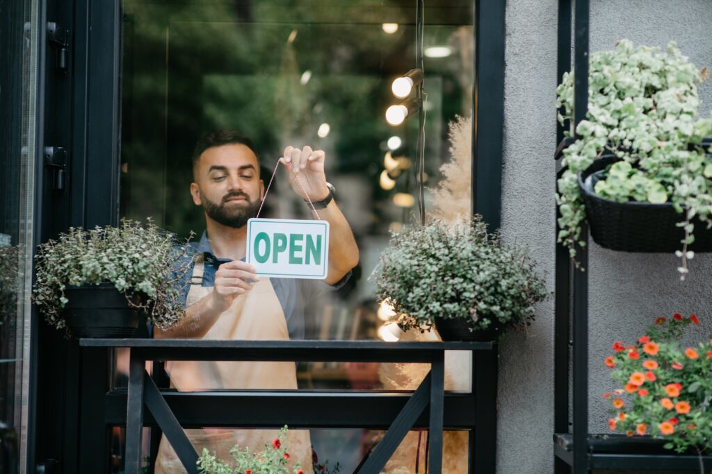 Shopkeeper turning their retail store sign to open. 